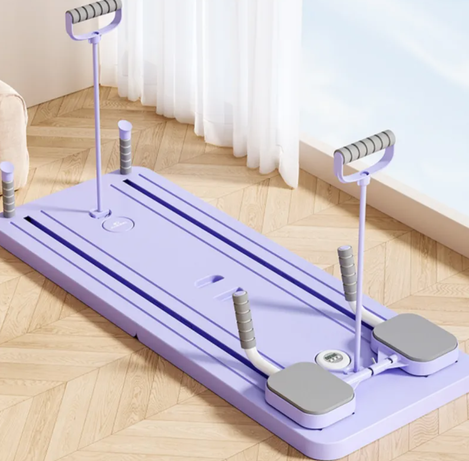Planche abdominale lilas avec supports à ressort, deux pédales grises et poignée centrale.