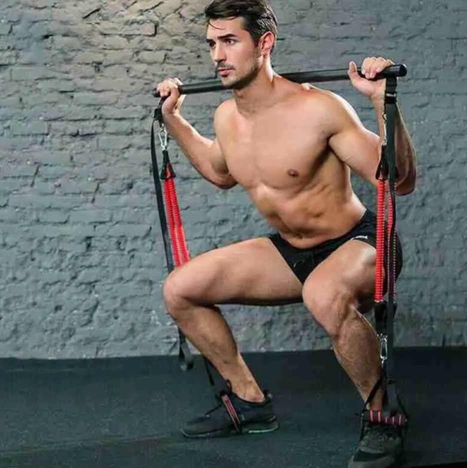Barre de pilates avec bandes rouges et poignées, en utilisation pour exercices