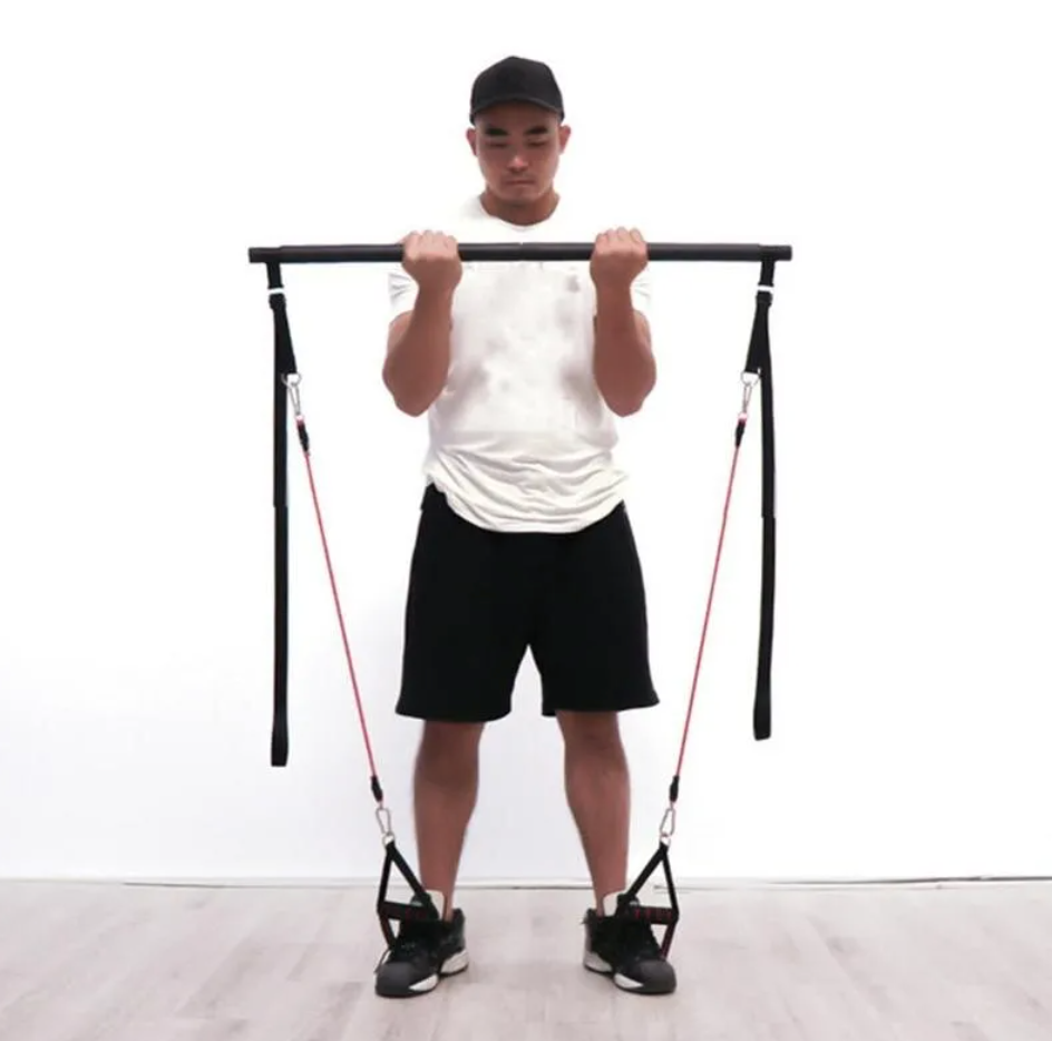 Barre de Pilates avec élastiques rouges, un homme tient la barre, sangles noires et crochets